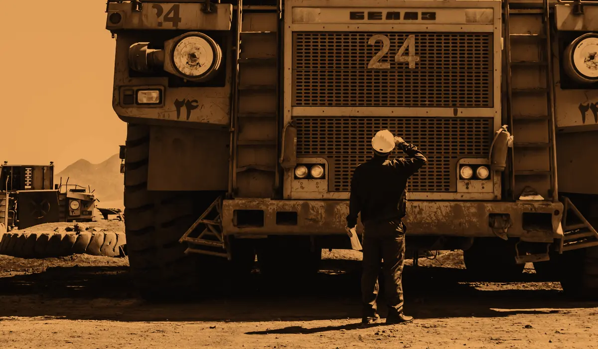 An engineer in a hard hat in front of a large mining haul truck