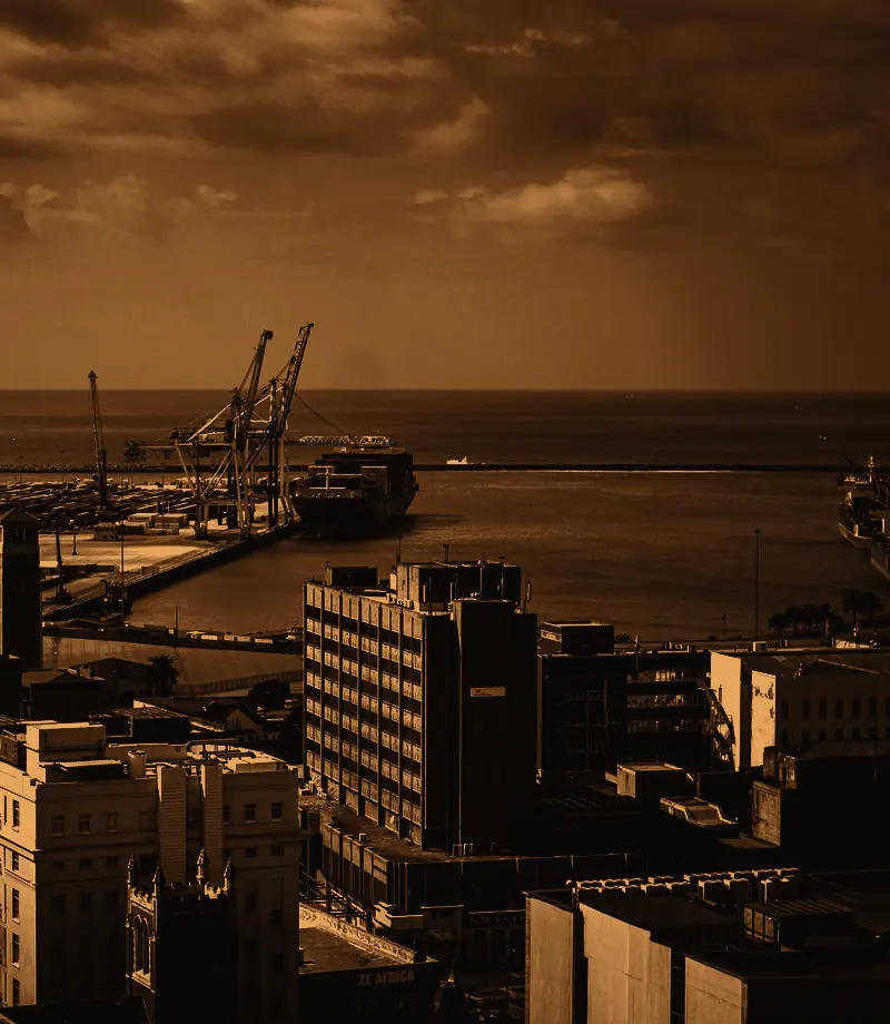 Harbour cranes loading a container ship beside city buildings