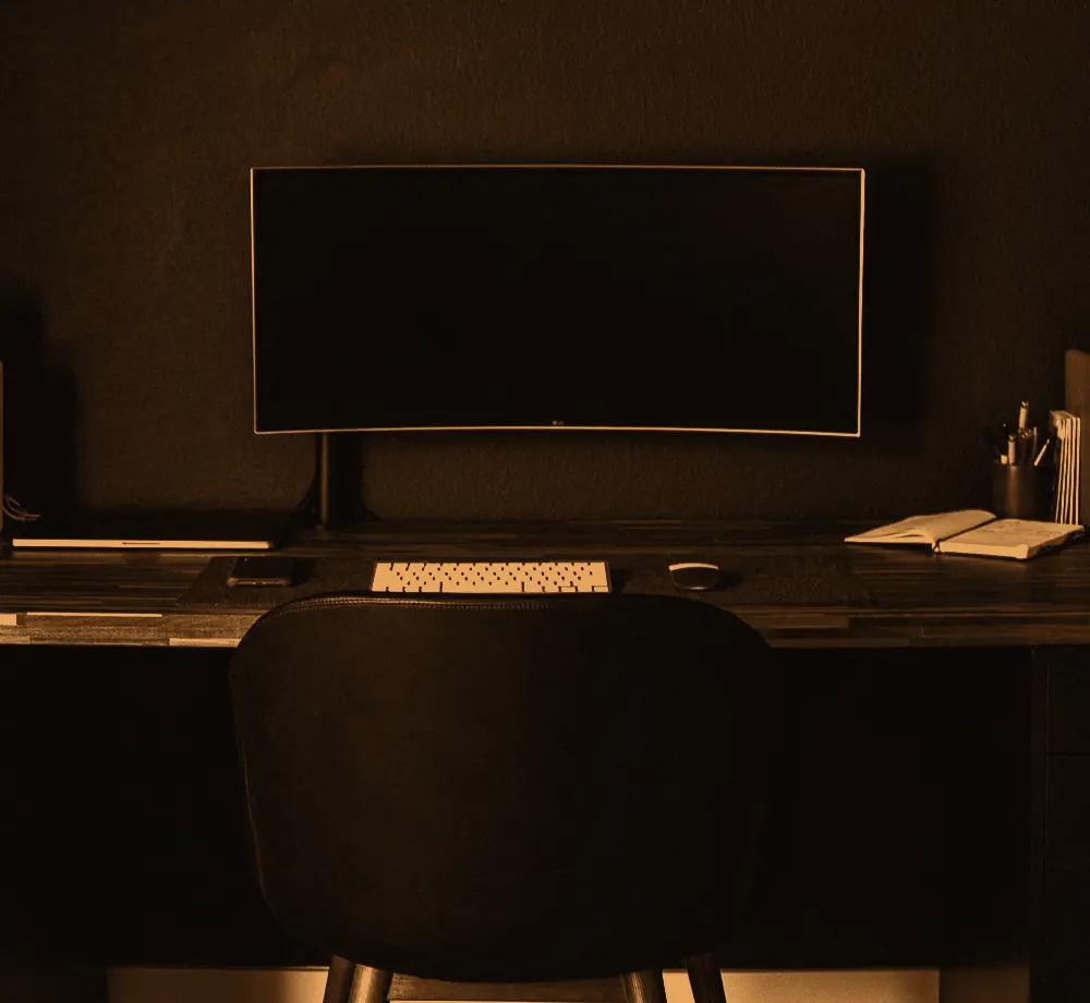 A quiet office desk with a widescreen monitor and keyboard